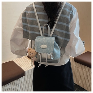 Vue arrière d'un mini sac à dos bleu clair avec détails argentés et charm ours en peluche