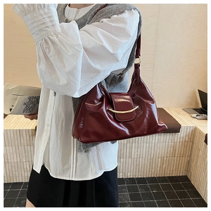 Close-up of deep wine red patent leather shoulder bag with crescent moon metal buckle