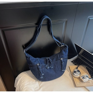 Détail d'un sac demi-lune en denim avec poches zippées et bandoulière réglable