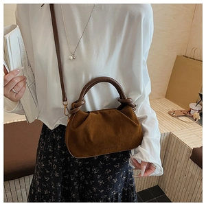 Detailed view of caramel brown pleated cloud bag with textured round handle and fine strap