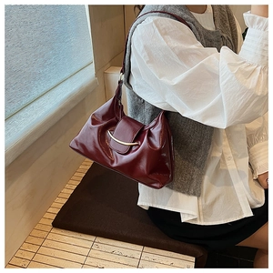 Detail of vintage burgundy dumpling bag featuring pleated leather and a gold metal bar