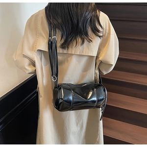 Detailansicht der glänzenden schwarzen Zylindertasche mit verstellbarem Riemen