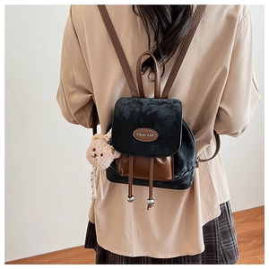 Détail du mini sac à dos en daim noir et cuir marron avec charmant pendentif ours