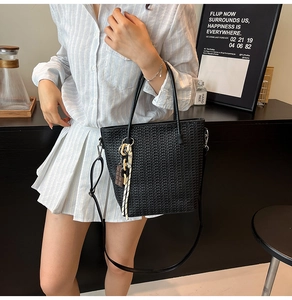 Close-up of black woven bucket bag showing detailed texture and detachable strap