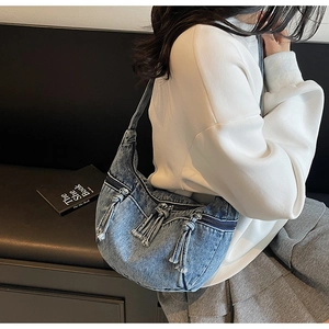 Détail d'un sac à épaule en jean bleu avec franges et fermetures éclair vintage