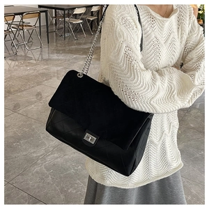 Close-up of black quilted tote bag with silver chain strap and metal swivel lock detail