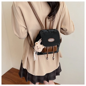 Détail du mini sac à dos noir et marron avec ours en peluche porté par un mannequin