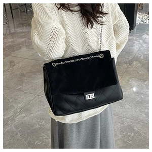 Detail of black quilted chain tote bag featuring mixed textures and silver turn-lock closure
