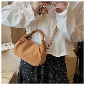 Close-up of brown pleated cloud bag with knotted handle and embossed fashion text