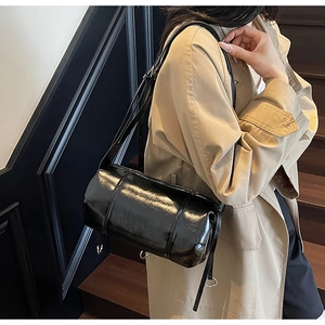 Detail einer schwarzen Lackleder-Zylindertasche mit Fransen und Schultergurt