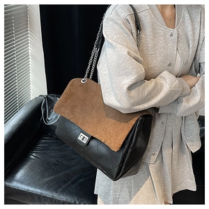 Detail of a large tote bag featuring black quilted leather and brown suede flap with chain