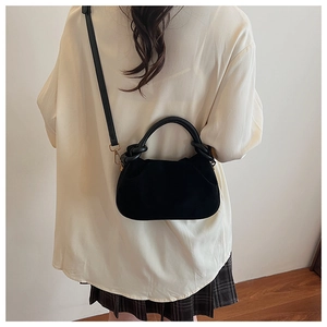 Close-up of black ruched croissant bag with gold metal hardware on model's shoulder