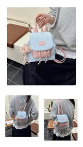 Détail du mini sac à dos bicolore avec fermeture à cordon et petit pendentif en peluche