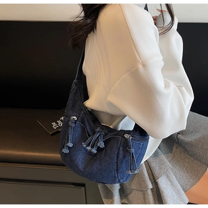 Détail du grand sac hobo en jean avec fermeture éclair à franges montrant le volume porté