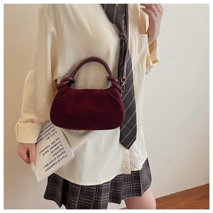 Detail of burgundy velvet cloud bag with knotted handle and gold metal hooks
