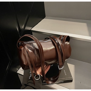 Detail der tiefbraunen zylindrischen Ledertasche mit Glanzfinish und dünnen Riemen