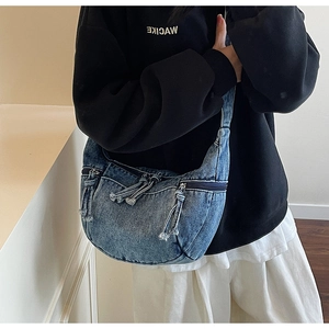 Détail du sac demi-lune en denim lavé bleu avec fermeture à glissière à franges en métal