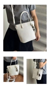 Detail view of white woven bucket bag with contrast resin chain and adjustable strap