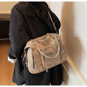 Dettaglio borsa shopper vintage in pelle marrone con cerniere a frange e tasche multiple