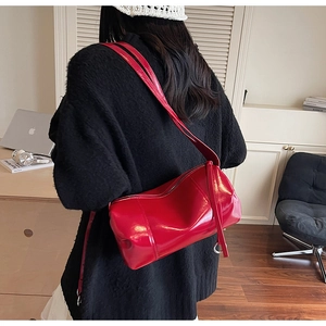 Detail der roten Zylindertasche aus Lackleder mit breitem Riemen am Model