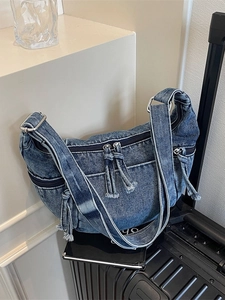 Sac croissant en denim rétro avec multiples poches et bandoulière sur une valise