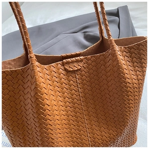 Gros plan sur la texture en cuir tressé marron et la finition du sac cabas chic