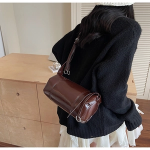 Detail der dunkelbraunen, glänzenden Boston-Tasche mit verstellbarem Gurt und Silber-Hardware