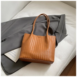 Vue détaillée de la texture tressée marron et des anses d'un grand sac cabas chic