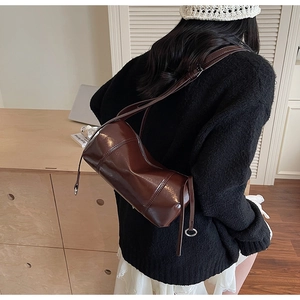 Detail einer glänzenden dunkelbraunen Zylindertasche mit poliertem Leder-Finish