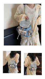 Detail of light blue denim mini backpack with silver leather trim and drawstring closure