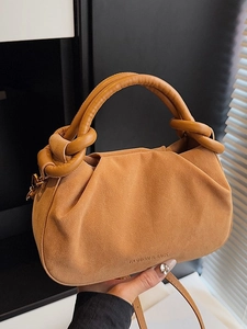 Brown suede ruched dumpling bag with top handle and strap shown in lifestyle view