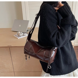 Nahaufnahme einer glänzenden schokobraunen Zylindertasche mit Metallreißverschluss und Gurt