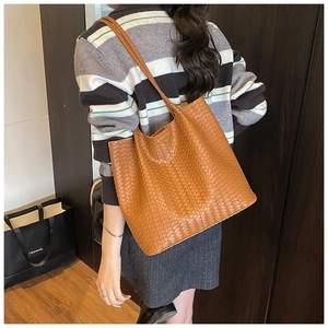 Vue détaillée du sac cabas tressé marron montrant sa texture riche et sa longue bandoulière