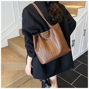 Détail du grand sac cabas en cuir tressé marron foncé porté par un mannequin pour le travail