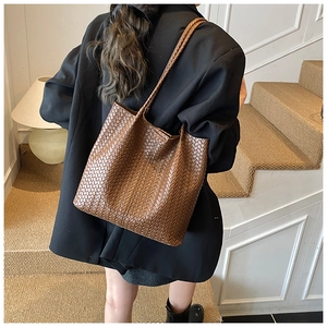 Détail de la texture en cuir tressé main sur un grand sac cabas marron pour femme