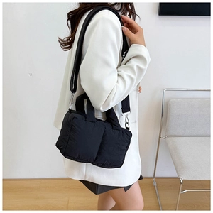 Detailed shot of black puffy quilted tote bag with front pockets on female model