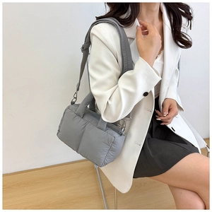 Detailed side view of a gray quilted puffy tote bag with a removable shoulder strap