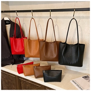 Détail de cabas tissés et pochettes assorties en rouge, marron, beige et noir