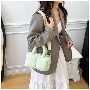 Detailed view of light green quilted puffy bag with handles and crossbody strap on a model