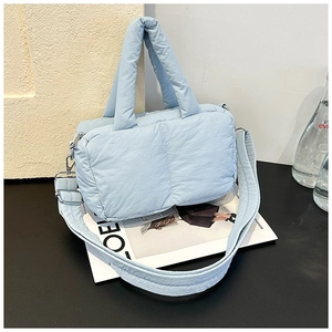 Detail of light blue quilted tote bag with padded handle and silver metal hook clasp