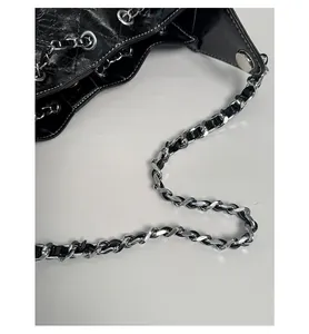 Détail d'un sac en cuir matelassé brillant avec œillets métalliques et bandoulière chaîne