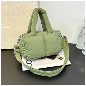Detail of avocado green quilted nylon tote bag with thick handles and wide crossbody strap