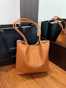 Sac cabas tissé en cuir caramel avec longues bandoulières sur bois naturel