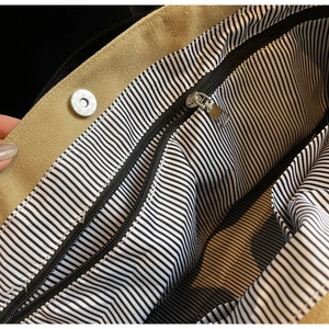 Detail of canvas tote bag showing striped lining, inner zipper pocket and magnetic closure
