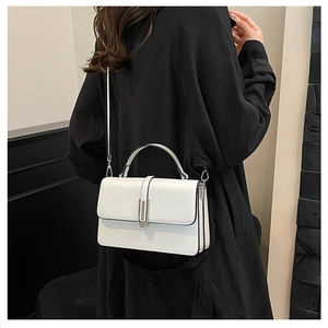 Detailed side view of white crossbody bag with accordion folds and silver metal buckle