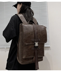 Side view of dark brown vintage faux leather backpack with silver metal buckles on model