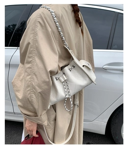 Détail du sac seau matelassé blanc avec bandoulière chaîne et petite poche latérale