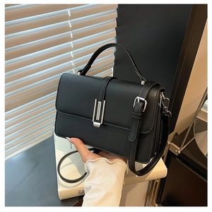 Detail of a black leather crossbody bag with silver buckle and adjustable shoulder strap