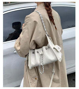 Détail d'un sac seau matelassé blanc avec bandoulière chaîne argentée sur un mannequin