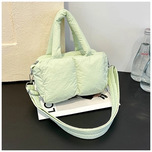 Detail of mint green quilted puffer bag with wide padded strap and silver hardware